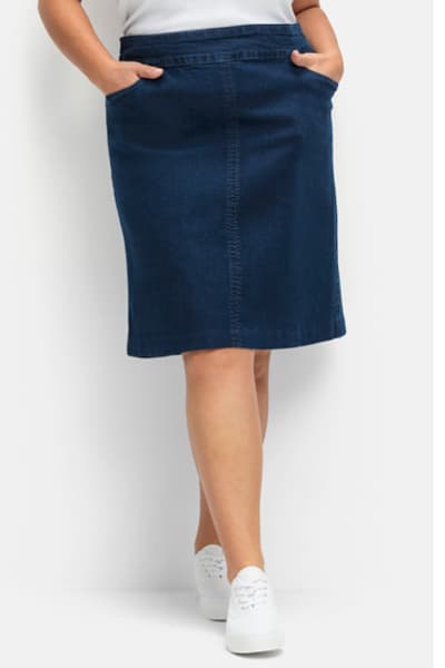 Ein Model trägt einen blue-stone-washed Jeansrock in dezenter A-Form mit Dehnbund und 2 abgerundete Taschen im Vorderteil.