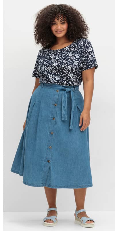 Ein Model trägt einen blue-bleached Jeansrock mit Knopfleiste in schwingender Form.