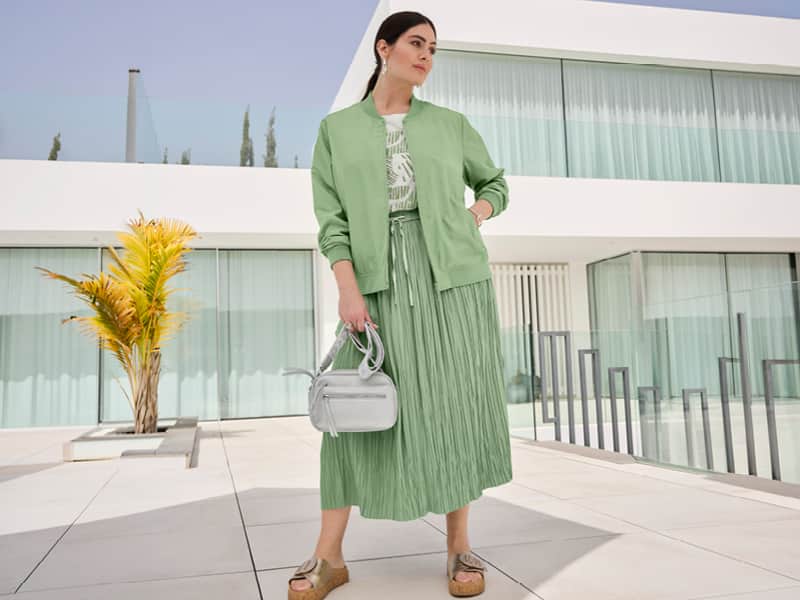 Ein Model trägt einen eucalyptus farbenen Midi-Sommerrock in Crinkle-Qualität.