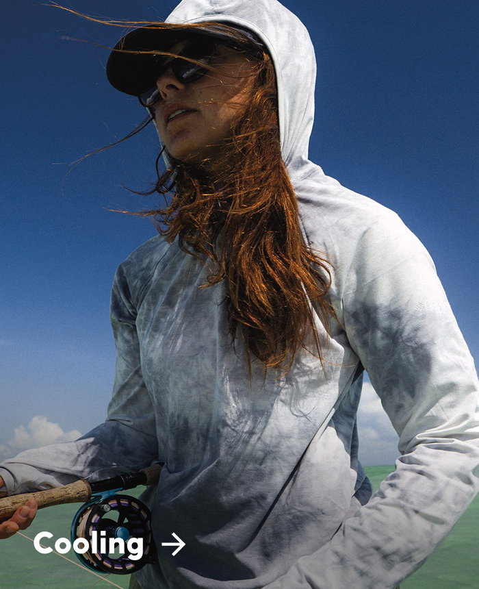 A woman standing in the water wearing a blue sun hoodie and holding a fishing rod with text: Cooling