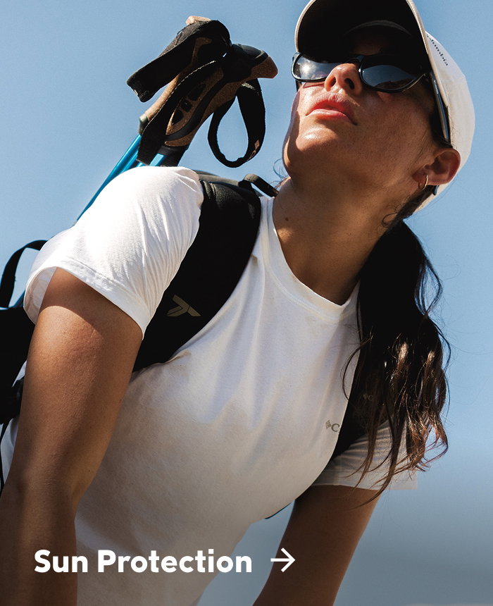 A woman in a white shirt, ball cap, and backpack against a blue sky with text: Sun Protection