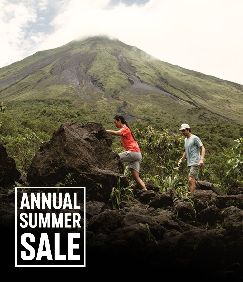 Two hikers exploring a volcano trail with text: ANNUAL SUMMER SALE