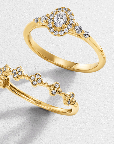 Yellow gold rings, one with an oval-cut halo engagement ring and one with diamond cluster flowers on band.