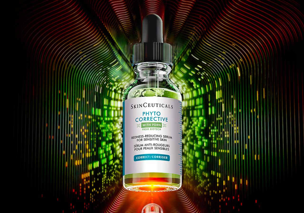 Flasche des SkinCeuticals Phyto Corrective Serum mit Pipette vor einem abstrakten, leuchtenden Hintergrund in Grün-, Rot- und Orangetönen.