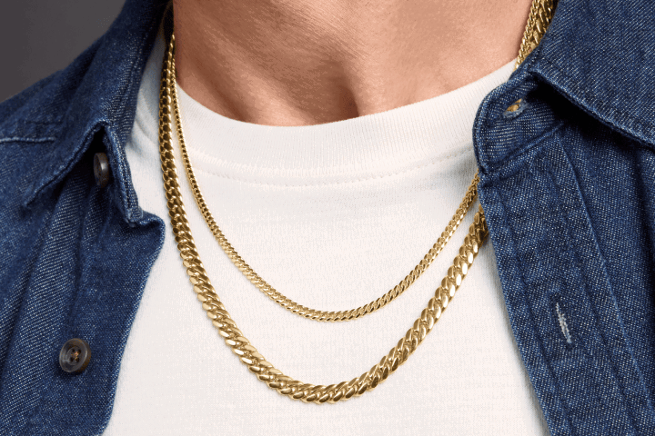 Layered gold chain necklaces styled with a denim shirt and white tee.