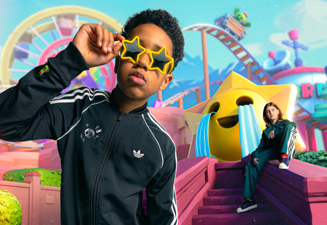 Person in a black adidas track jacket wearing star-shaped sunglasses in a colorful fantasy setting.