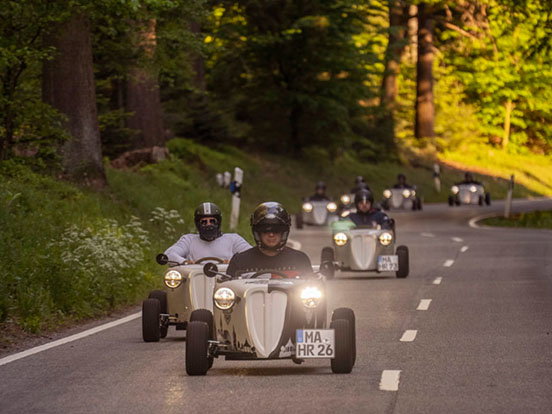 Personen sitzen in Hot Rods Fahrzeugen.