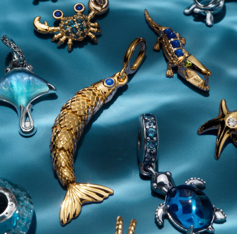 Two sterling silver turtle charms from Pandora Moments on a blue background.