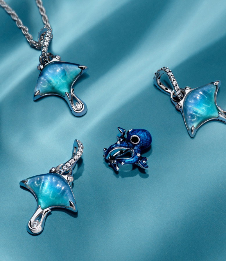 Two sterling silver turtle charms from Pandora Moments on a blue background.