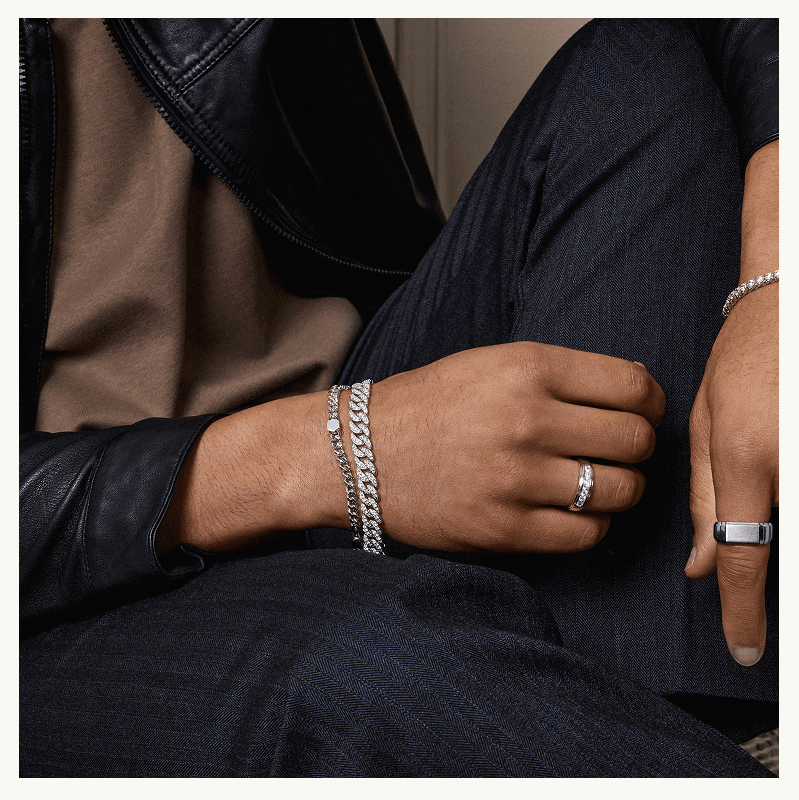 Male model in diverse silver chain bracelets & rings with diamond accents.