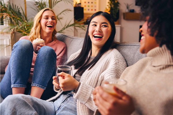 A group picture of three friends laughing on the sofa drinking Whittard tea, coffee and hot chocolate