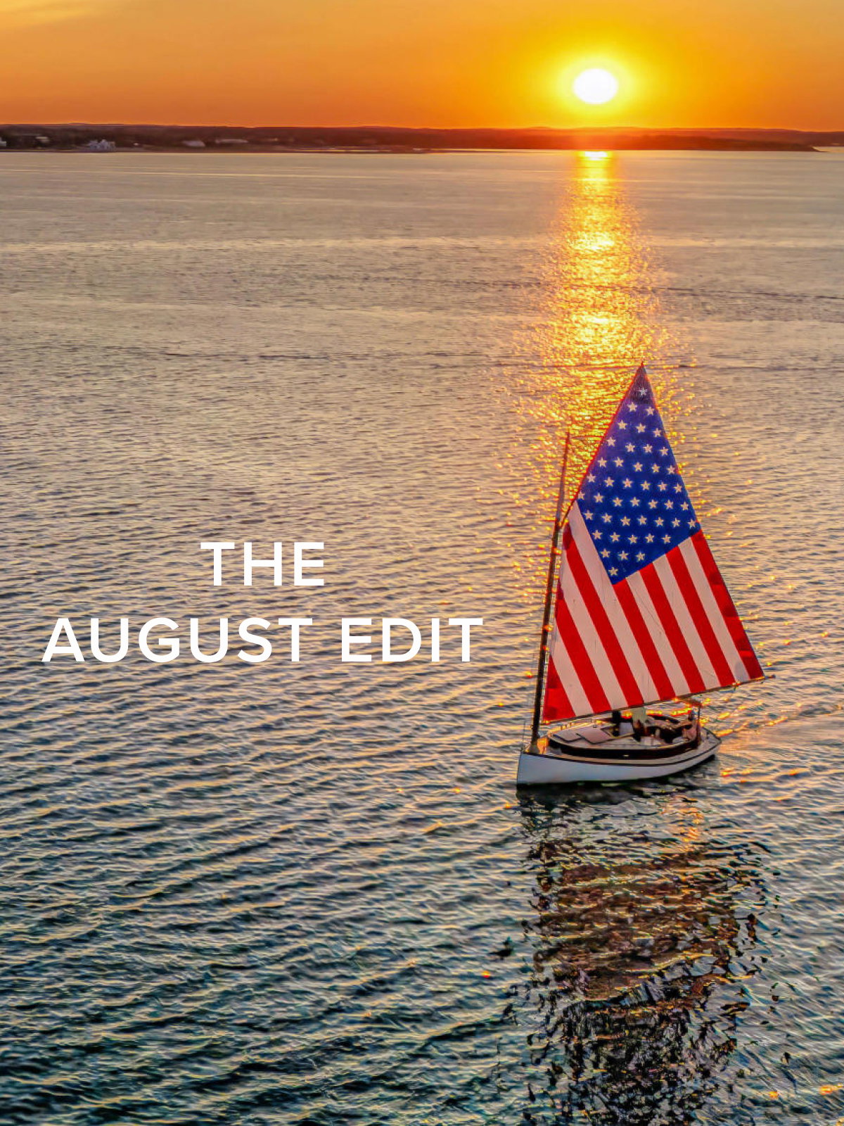 A sail boat with an American flag sail in he water amongst an east coast sunset