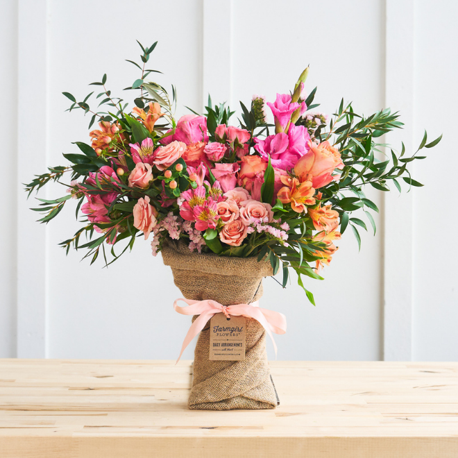 Pink and coral flowers with trailing greenery in burlap wrap. Hand Tied Bouquet, Fun Size. Shop now.