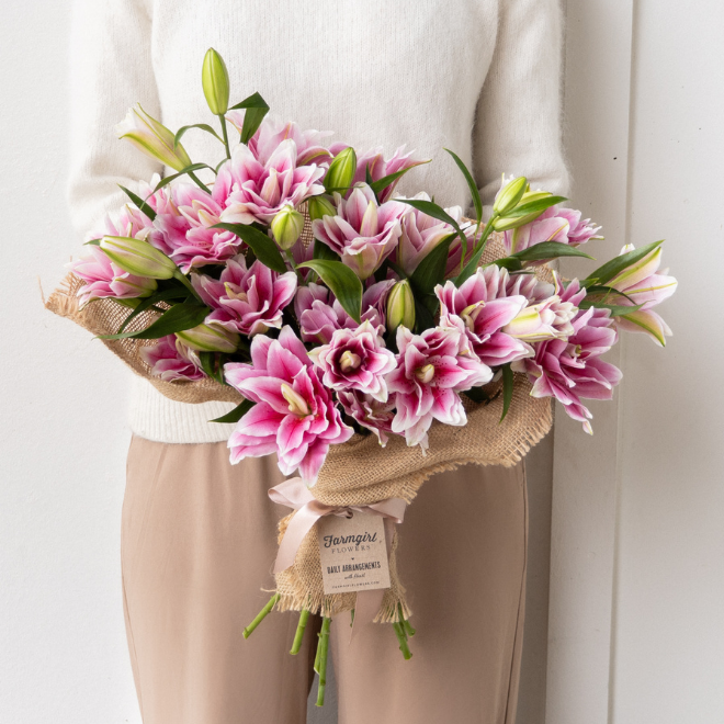 An armful of pink lilies in burlap wrap. Frill Seeker. Shop now.