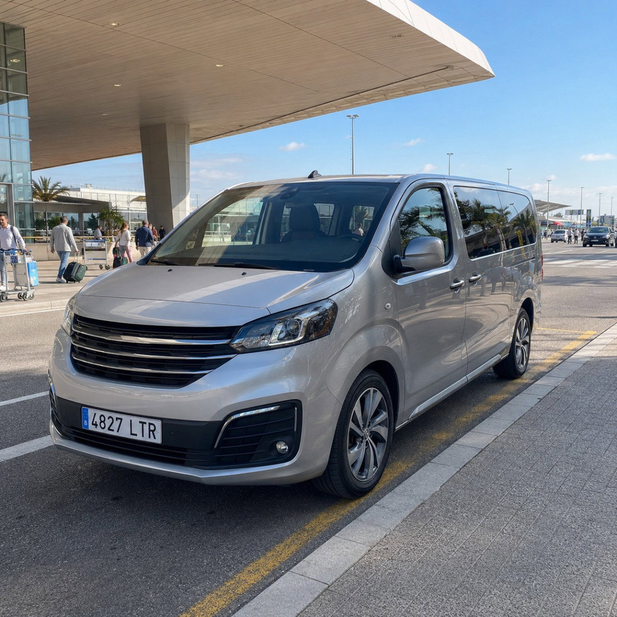 Silver passenger van parked outside an airport terminal.