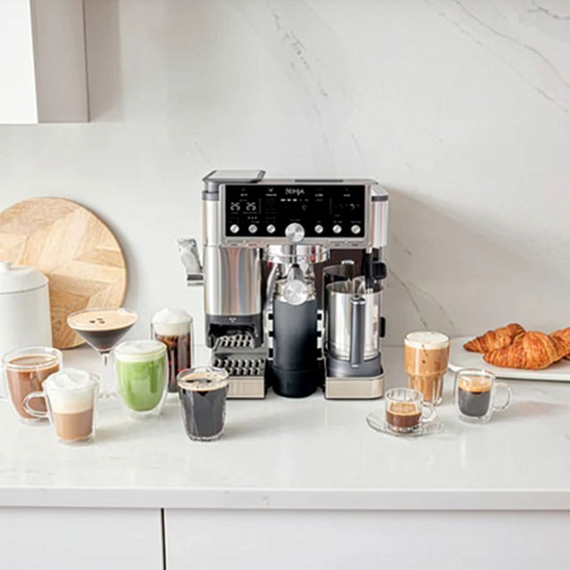 A coffee machine on a countertop with various coffee drinks and a croissant.