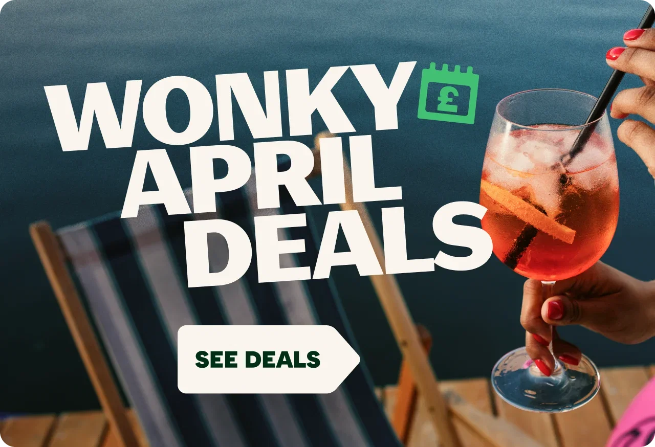 Promotional graphic advertising 'Wonky April Deals' Large white text reads 'WONKY APRIL DEALS' alongside a green calendar icon with a pound symbol. In the background, a person holds and stirs a red-orange iced drink in a wine glass near a waterfront setting. A white arrow-shaped button at the bottom reads 'SEE DEALS'.