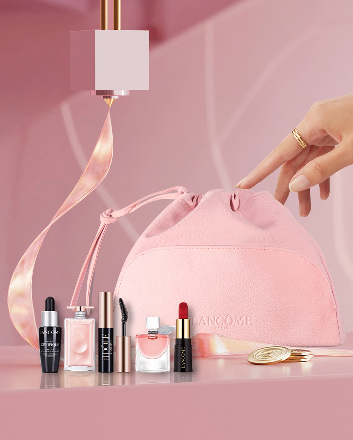 Pochette rosa Lancôme con vari prodotti cosmetici in miniatura e una mano che la sfiora.