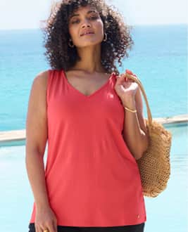 Model am Meer mit roten Strandtop und schwarzer Strandhose und link in die Strandmode