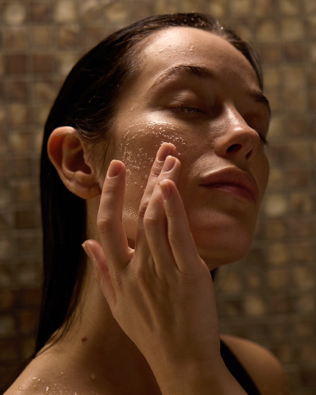 Model washing face in the shower