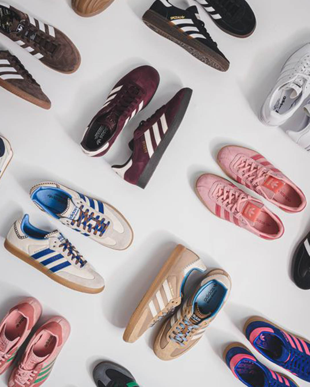 Top-down view of assorted Adidas trainers in various colours arranged on a white background