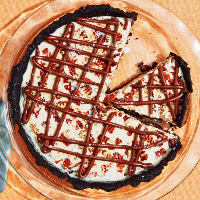 Overhead view of a frozen Mississippi mud pie with an Oreo cookie crust, coffee ice cream filling, toasted pecans, and a chocolate fudge drizzle.