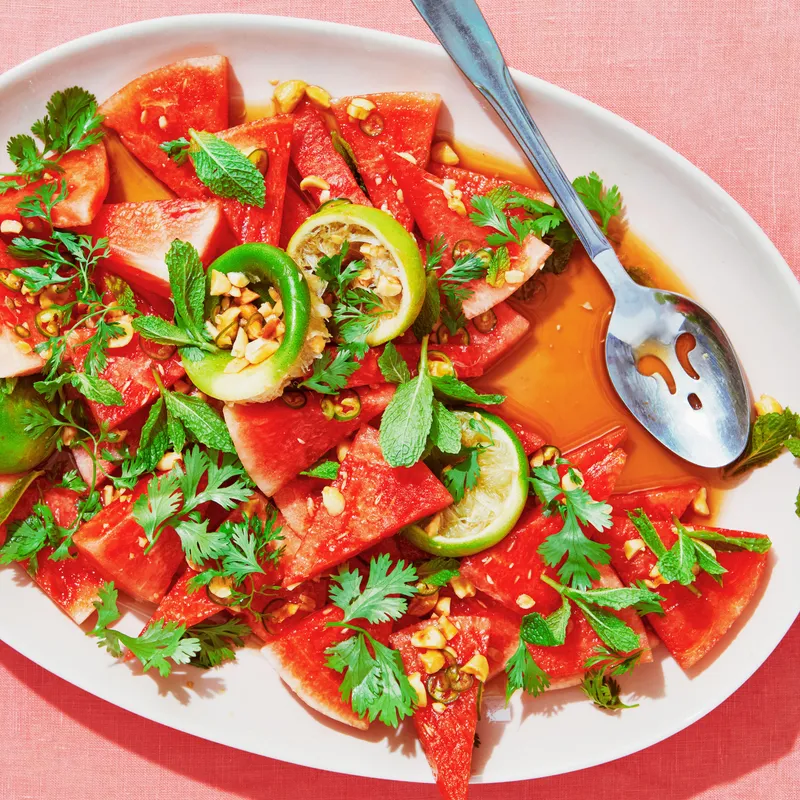 Watermelon cut into triangles, crushed peanuts, and limes tossed in fish sauce, lime juice, brown sugar, and salt and topped with mint leaves.