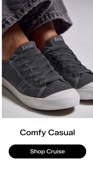 A light grey background with an angled view of the Cruise Canvas Slip-On in black paired with black denim.  Comfy Casual Shop the Cruise