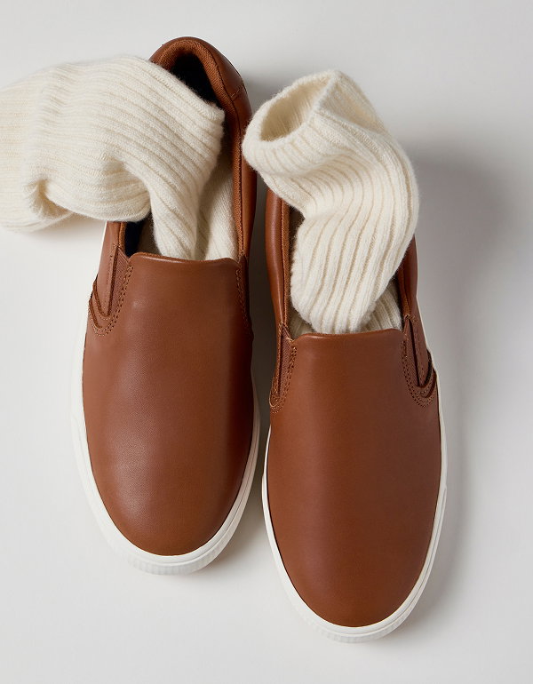 An overhead view of the Pursuit Leather Slip-On in cognac brown with cream ribbed socks inside.  Everlasting Effortlessness Shop the Pursuit Slip-On