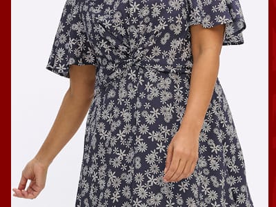 Ein Model trägt ein tiefblau-champagner-bedrucktes Blumenkleid mit Knotendetail