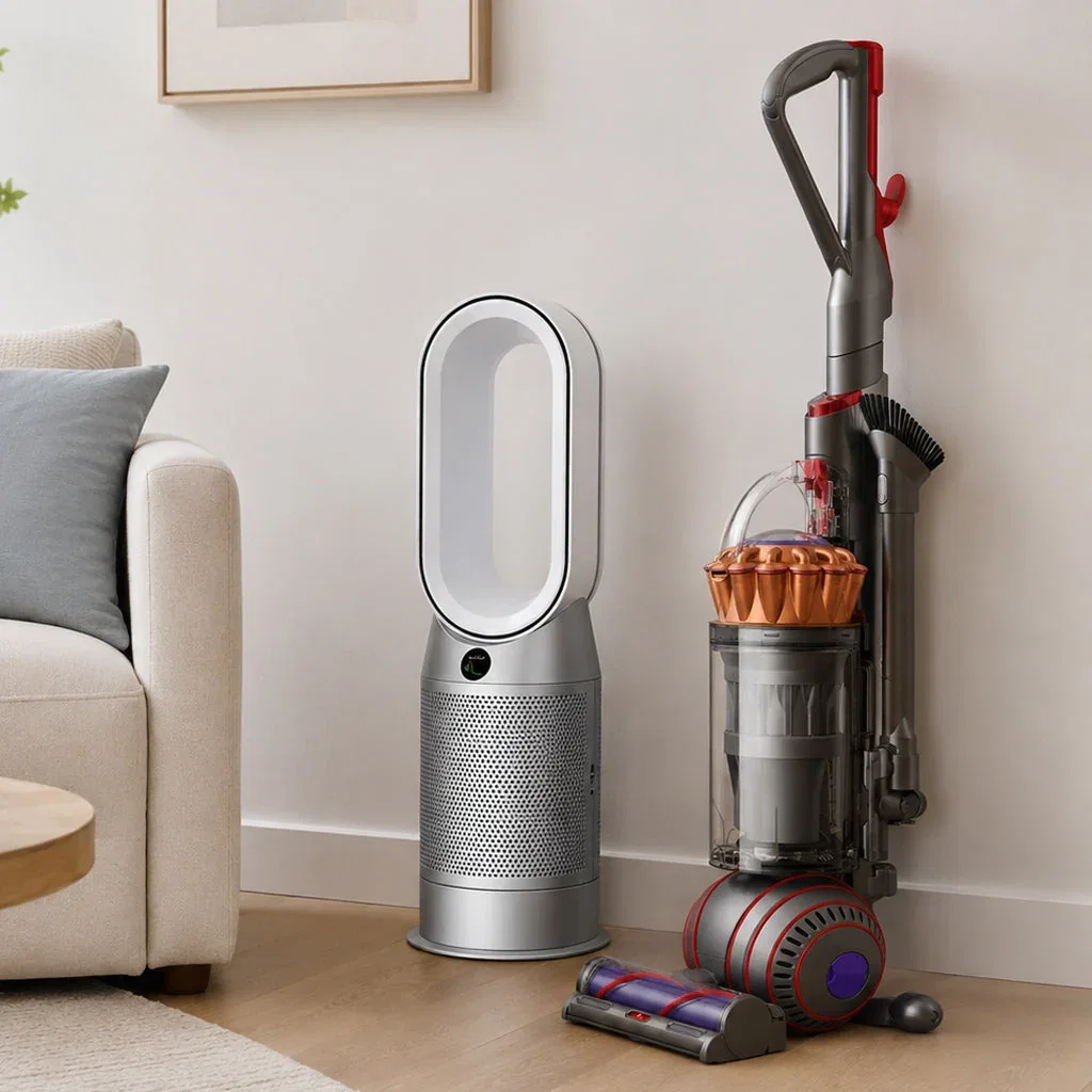 Dyson innovative technology collection featuring a silver air purifier, upright vacuum cleaner with red accents, and accessories on wooden floor next to beige sofa.