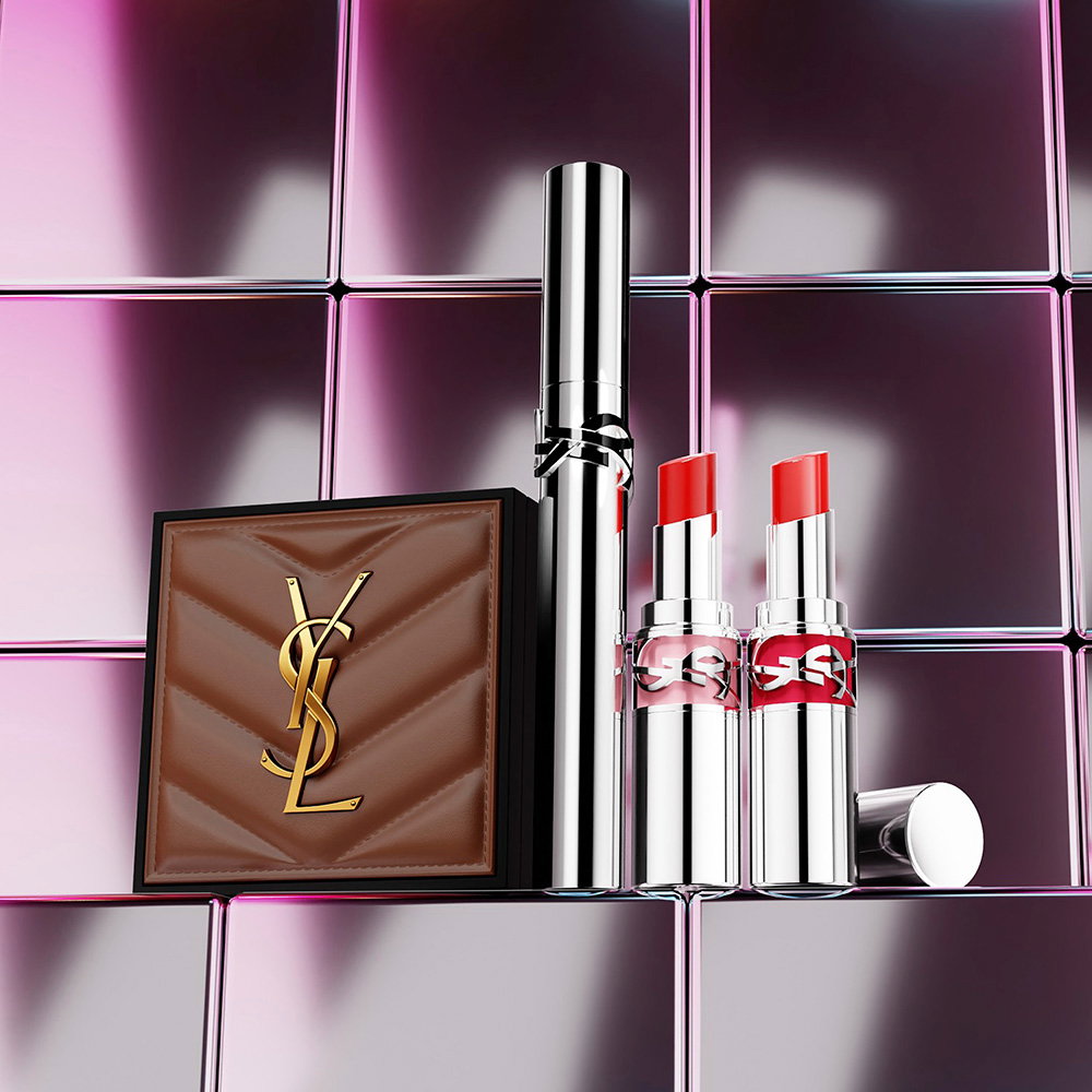 A brown quilted YSL leather case, a mascara, and two lipsticks displayed against a metallic tile background.