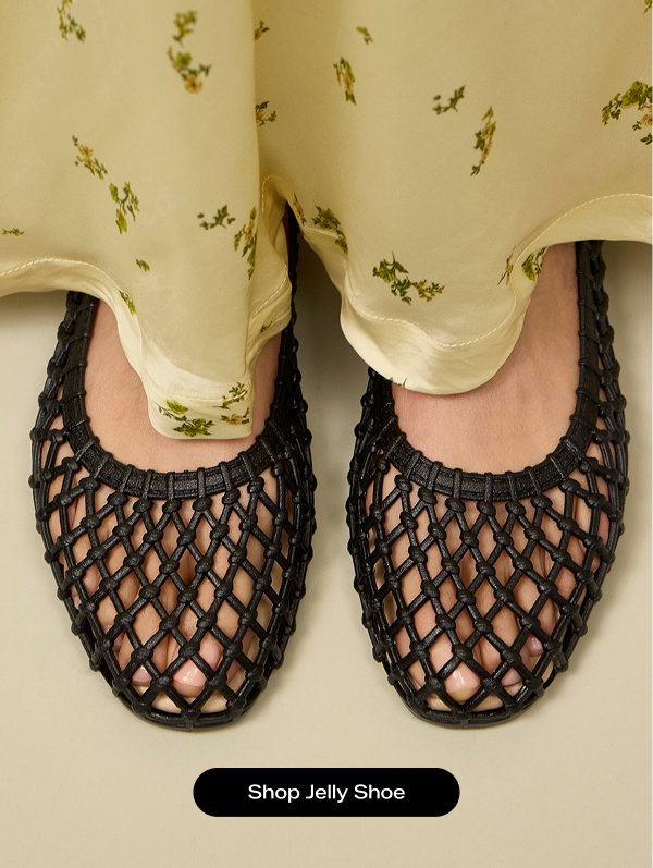 The top-down view of the Jelly Shoe in black shown on foot paired with a muted yellow floral print silk maxi skirt. Shop Jelly Shoe.