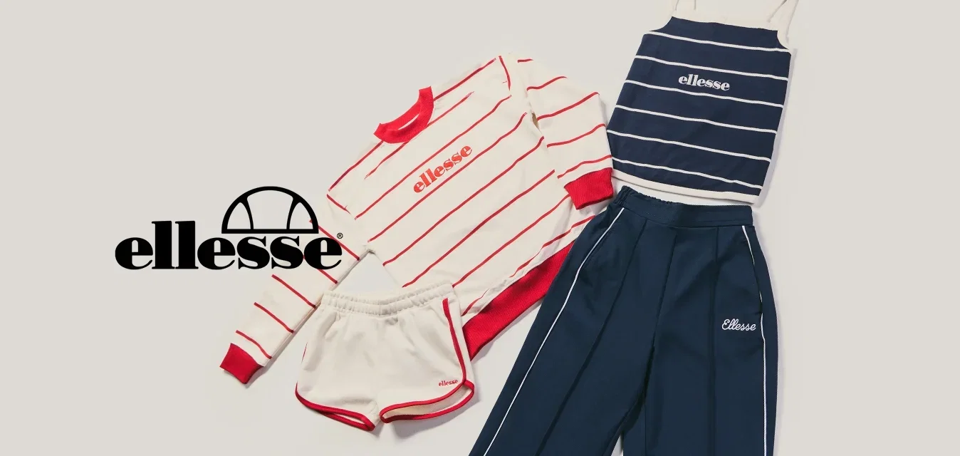 Legeres Sportset mit rot gestreiftem Sweatshirt, weissen Shorts, marineblau gestreiftem Tanktop und navy Trainingshose auf hellem Hintergrund ausgelegt.