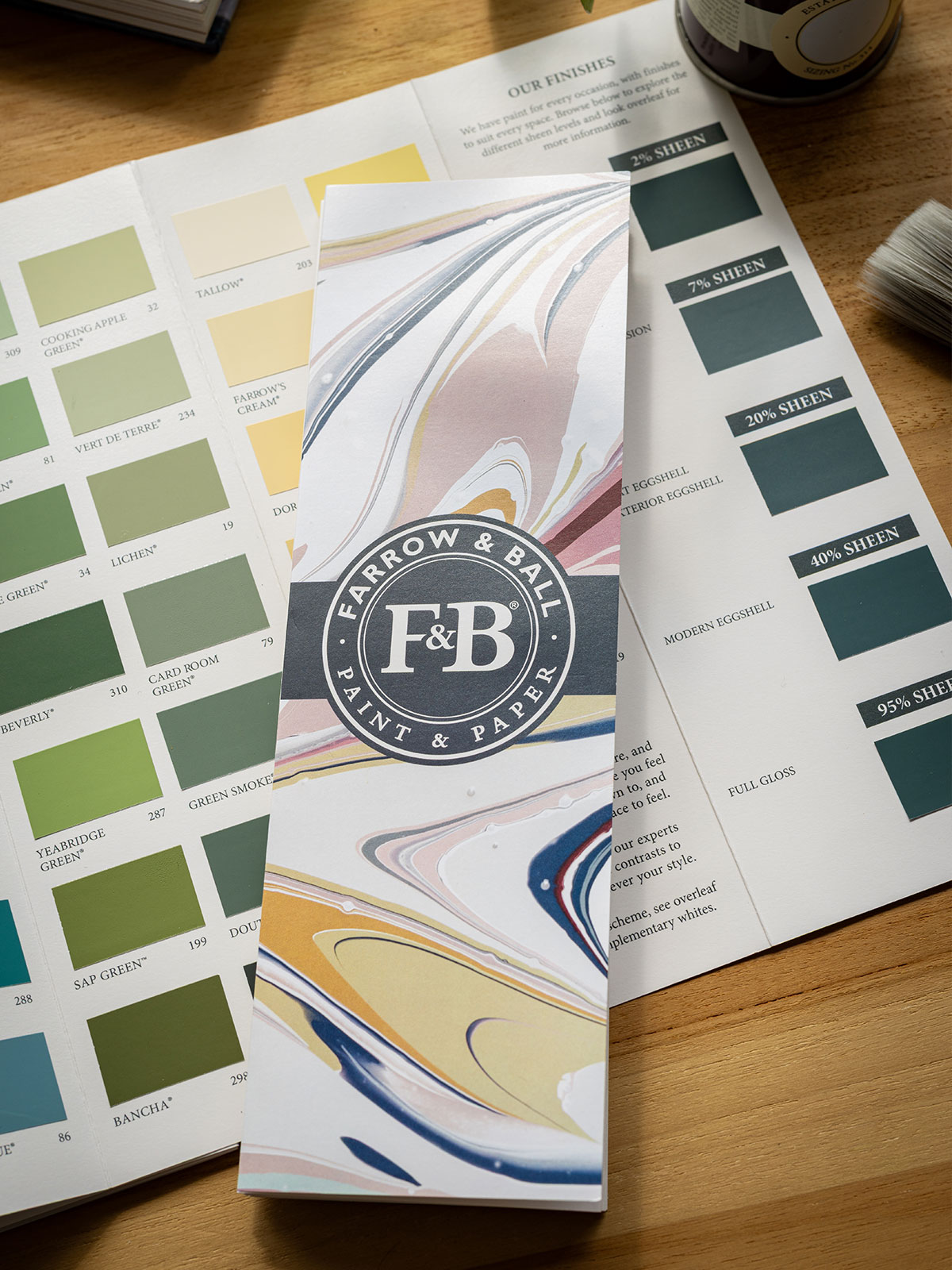 Farrow & Ball paint brochure on a table surrounded by colour charts and finishes.