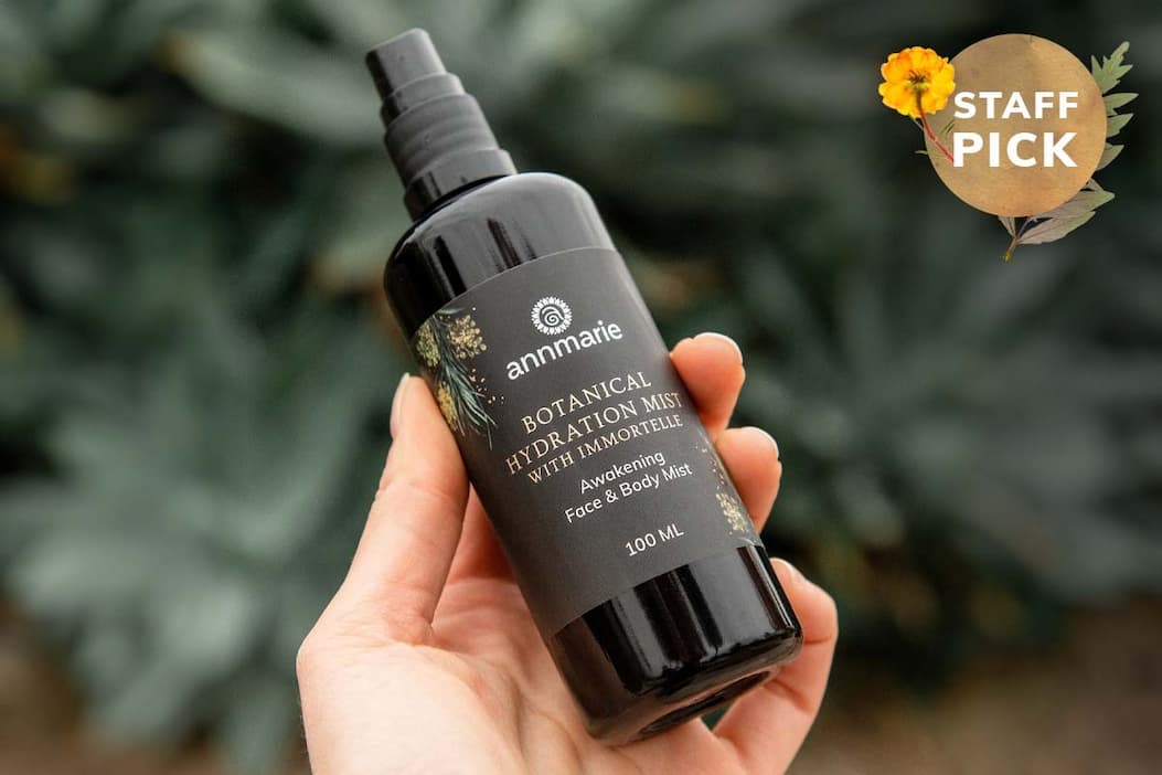 Hand holding the full-size (100ml) bottle of the Botanical Hydration Mist with Immortelle