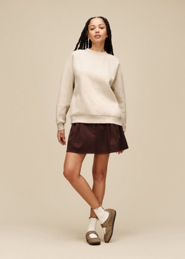 A model in a studio wearing a cream UGG jumper, a skirt and UGG shoes.