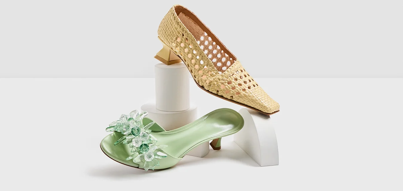 Due paia di scarpe: un pump giallo in paglia intrecciata con punta affilata e uno slide verde menta con decorazioni floreali e un tacco spesso.