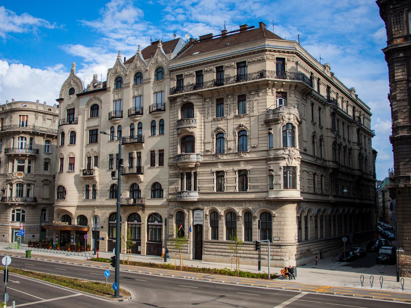 Ornate historic stone hotel and apartment building on a sunny city corner with blue sky