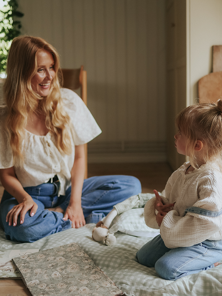 woman playing with child on blanket