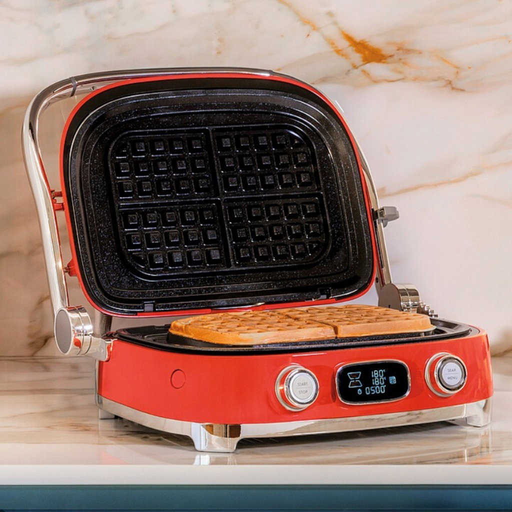 Grill Multiusos Smeg rojo con placas para gofres y gofres recién hechos sobre una encimera de cocina