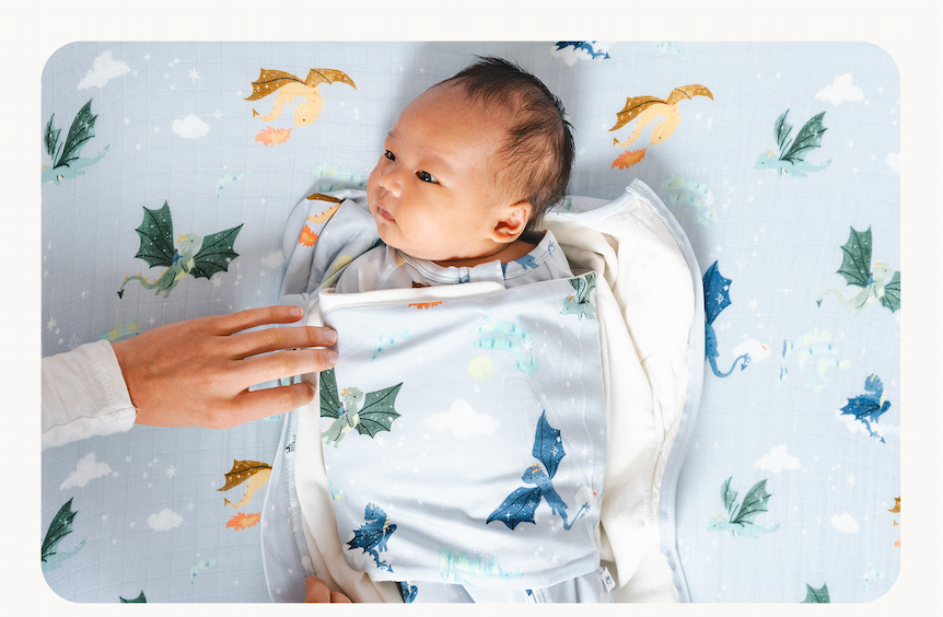 newborn being wrapped in a blue dragon printed swaddle wrap