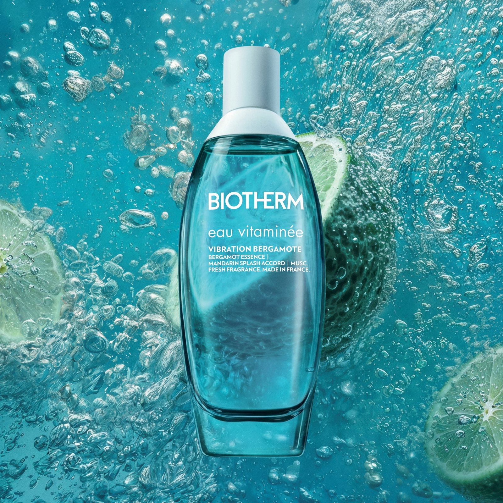 Botella de Eau Vitaminée Vibration Bergamote sobre fondo acuático azul con limones.