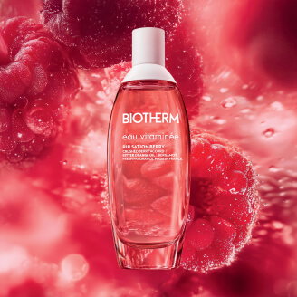 Botella de Eau Vitaminée Pulsation Berry sobre fondo de frambuesas y agua.