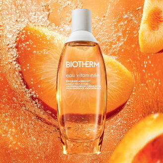  Botella de Eau Vitaminée Énergie Abricot sobre fondo cálido con albaricoque.