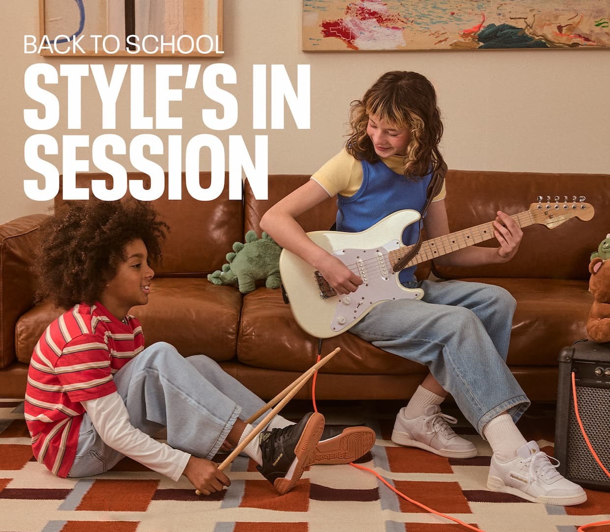 Two kids wearing white Reebok Classic sneakers play music together in a living room. Text reads: “BACK TO SCHOOL. STYLE’S IN SESSION.”