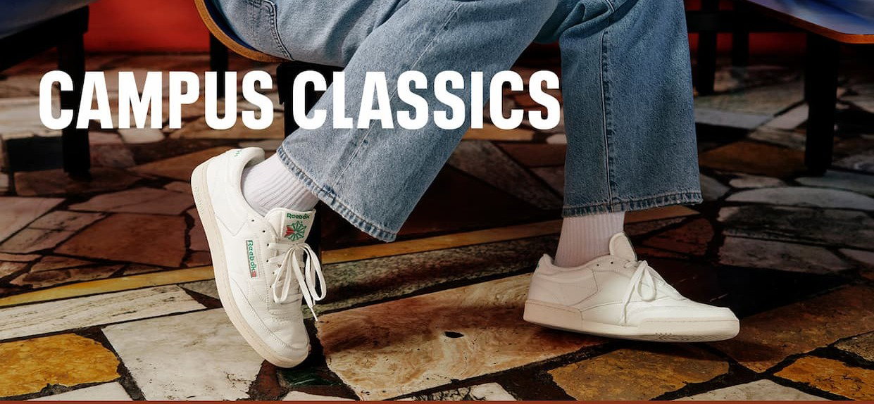 Close-up of white Reebok Club C 85 sneakers worn with jeans. Text reads: “CAMPUS CLASSICS.”
