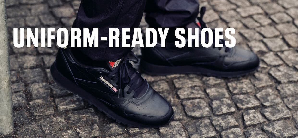 Close-up of black Reebok Classic Leather suitable for school uniforms worn outdoors. Text reads: “UNIFORM-READY SHOES.”