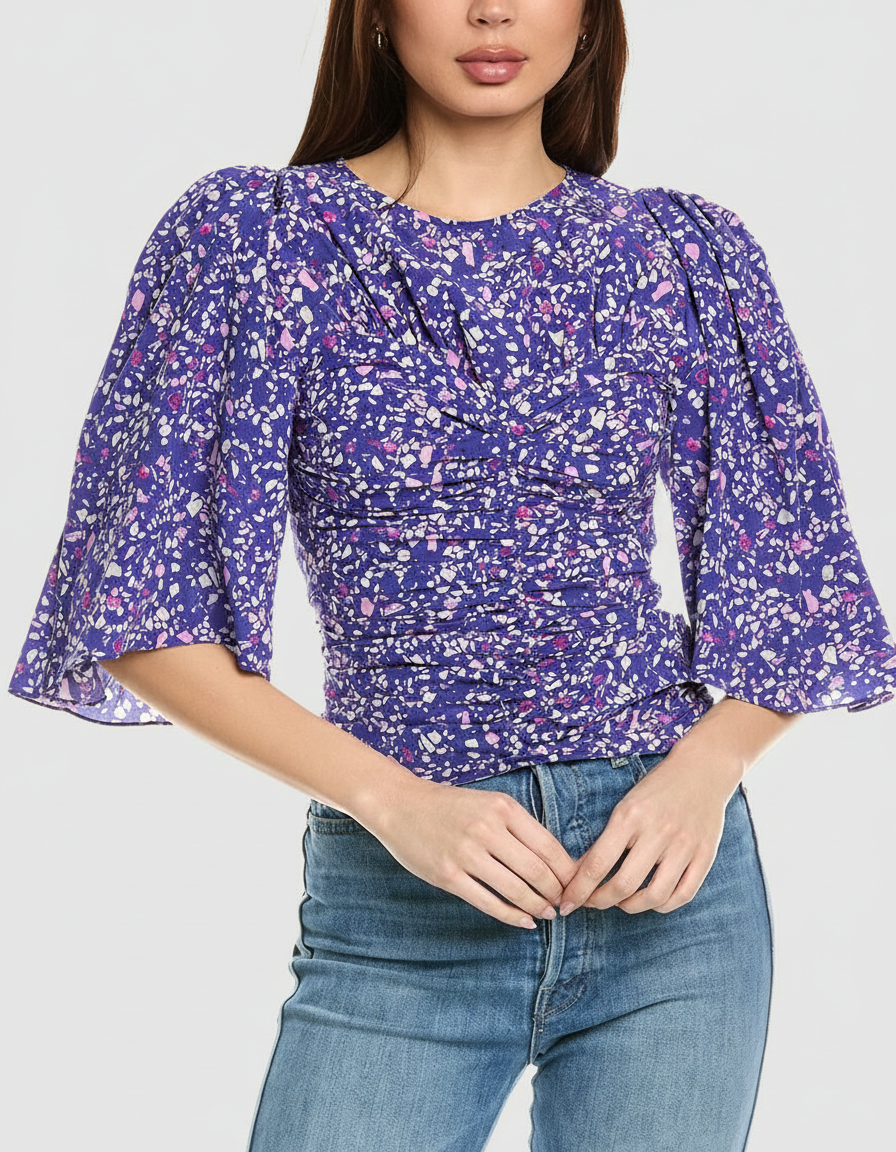 Woman in a purple floral ruched top and blue jeans.