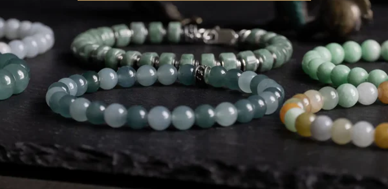Collection of jade beaded bracelets on dark surface